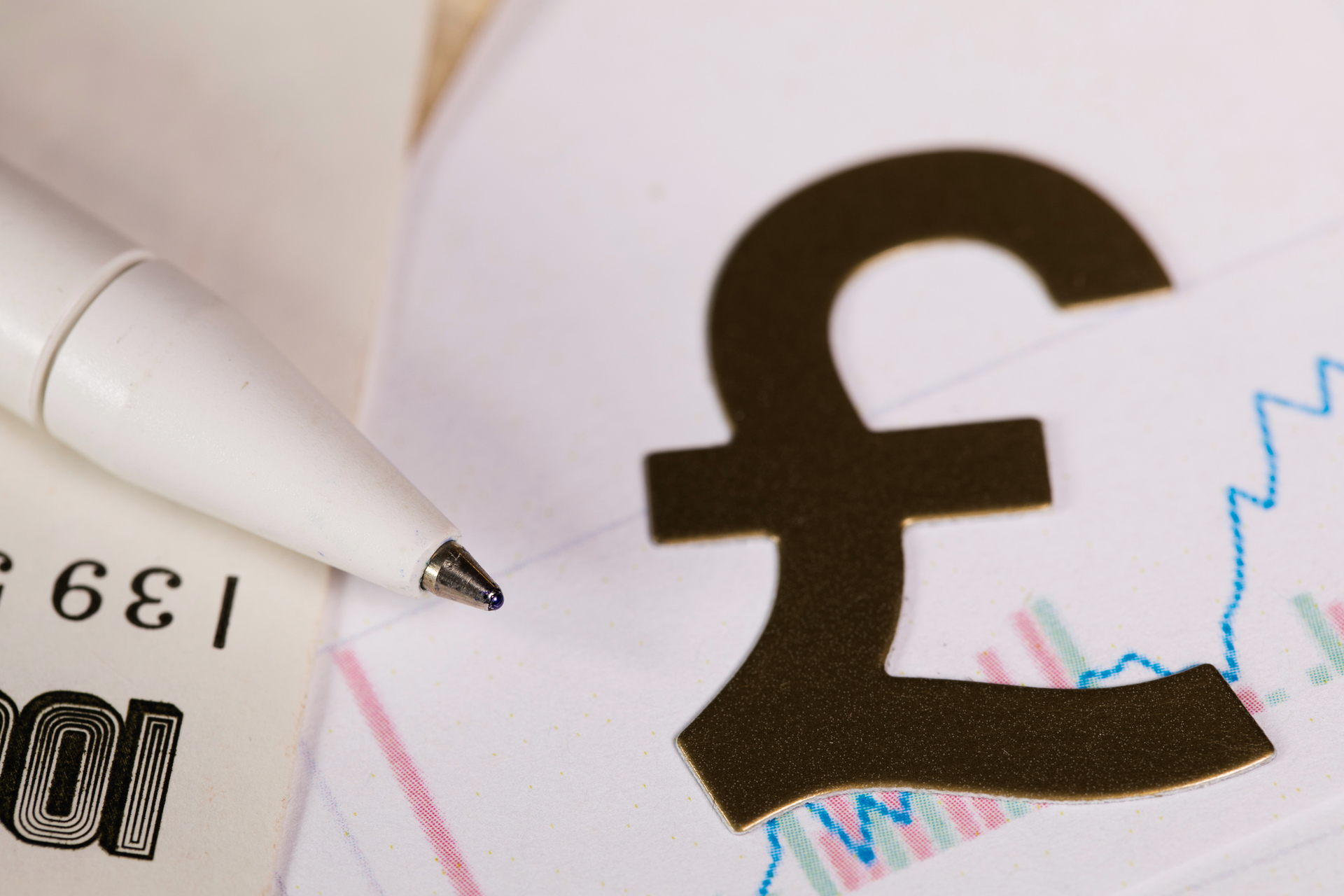 Pen on banknote, next to a British Pound sign
